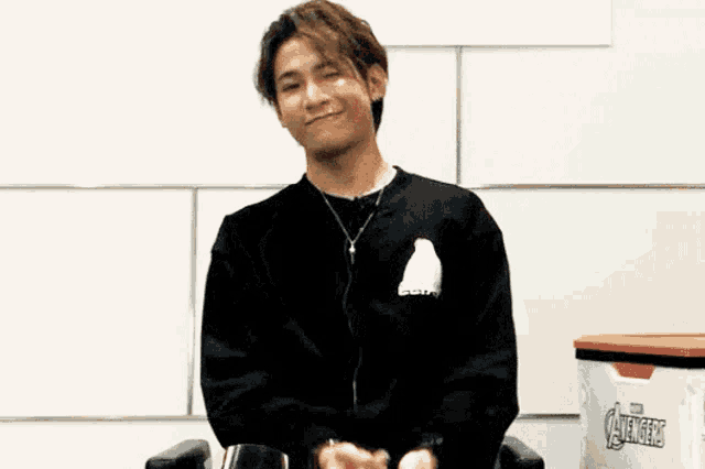 a young man wearing a black sweatshirt with the word avengers on the back