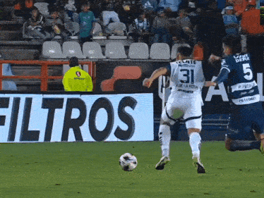 player number 31 kicks a soccer ball in front of a sign that says filtros