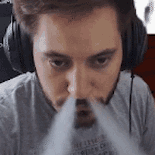 a man wearing headphones is blowing smoke out of his mouth ..