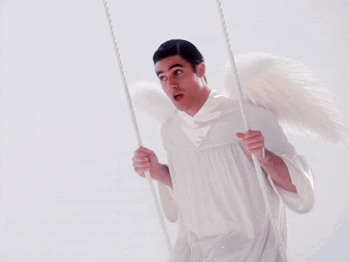 a man dressed as an angel is swinging on a swing