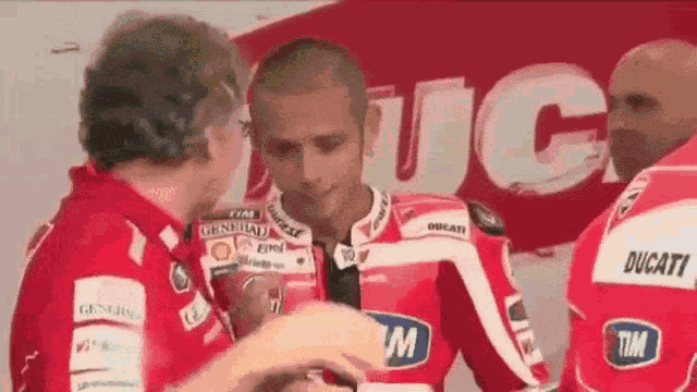 a man in a ducati jacket is talking to another man