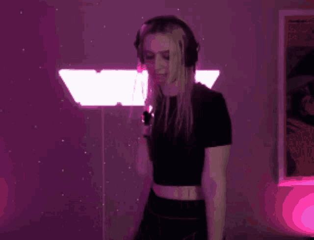 a woman wearing headphones and a black top is dancing