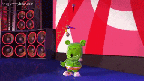 a gummy bear is dancing on a stage with a microphone and speakers behind him .