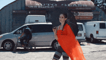 a woman holding an umbrella walks in front of a building that says auto glass