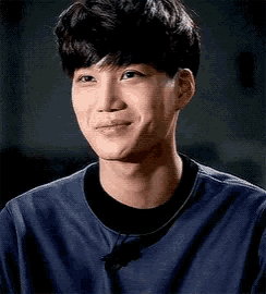 a close up of a young man wearing a blue shirt making a silly face .