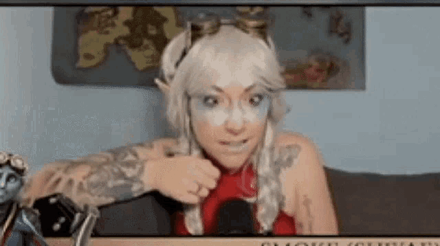 a woman in a cosplay costume is sitting in front of a microphone and making a funny face .