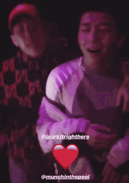 two men are hugging each other in a dark room with a red heart in the foreground that says munchinthepool