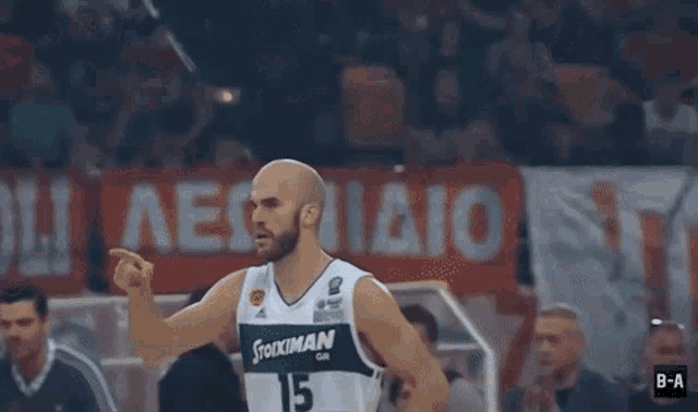 a basketball player with the number 15 on his jersey stands in front of a crowd