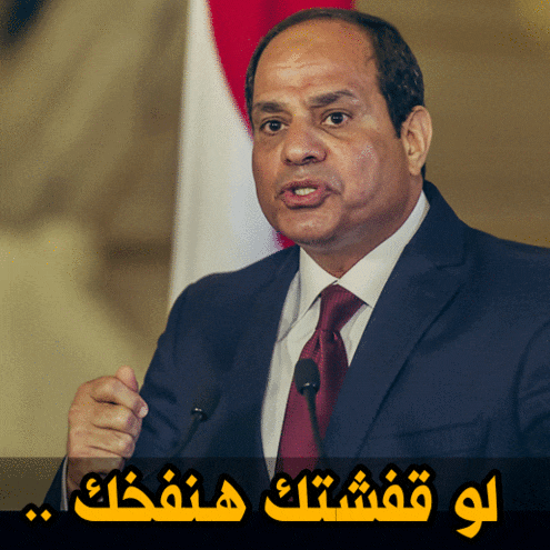 a man in a suit and tie speaking into a microphone with arabic writing below him