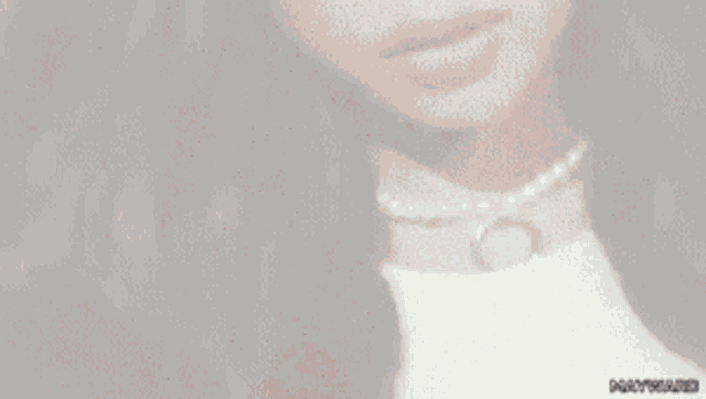 a close up of a woman 's neck with a pearl necklace