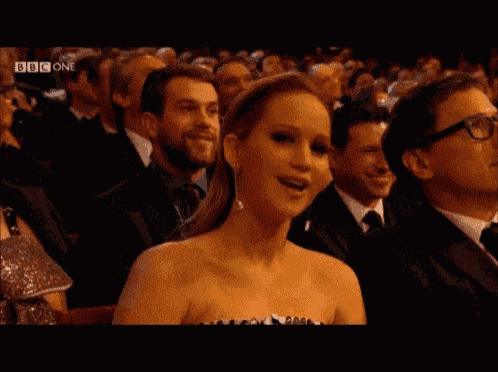 a woman in a strapless dress is sitting in a crowd with bbc one written on the bottom of the screen