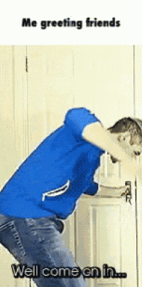 a man in a blue shirt is standing in front of a door and says well come on in