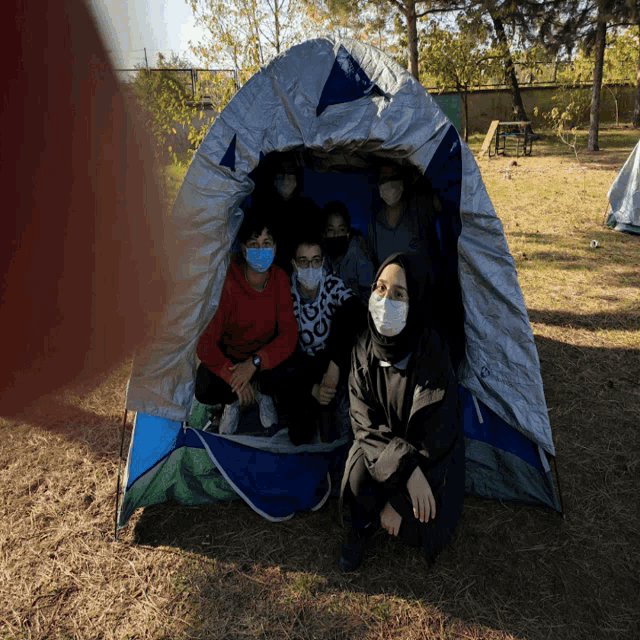 a group of people wearing masks are sitting inside a tent