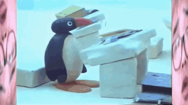 a cartoon penguin is sitting at a desk with books