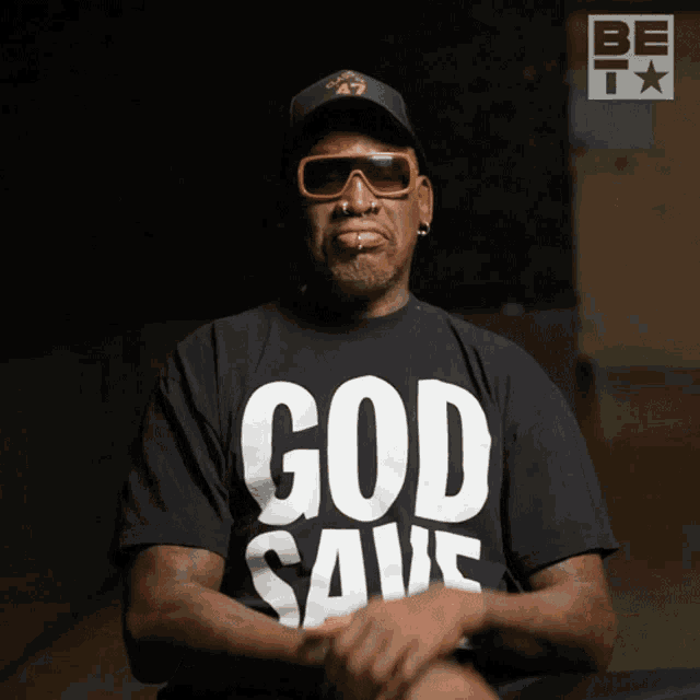 a man wearing a black shirt that says god save on it