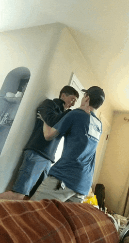 a man wearing a nasa hat is hugging another man in a blue shirt