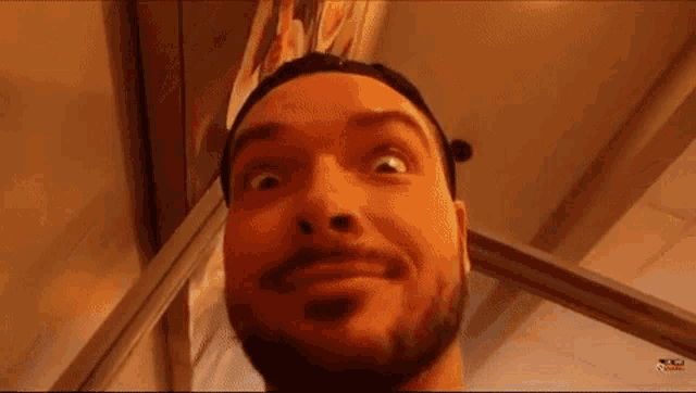 a man with a beard and hat is making a funny face .