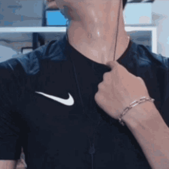 a man wearing a black nike shirt is standing in front of shelves .