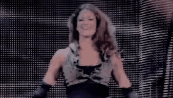 a woman in a black dress is standing in front of a large screen and smiling .