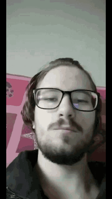 a man with a beard wearing glasses looks at the camera