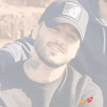 a man with a beard is wearing a black baseball cap and smiling