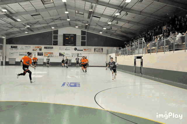 a group of people are playing a game of handball in a gym with a sign that says imgplay on the bottom
