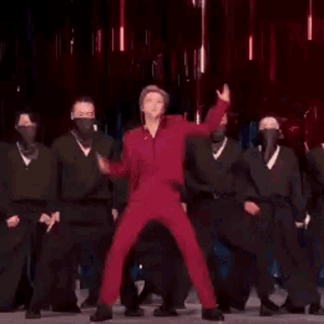 a man in a red shirt is dancing on a stage while wearing a microphone .
