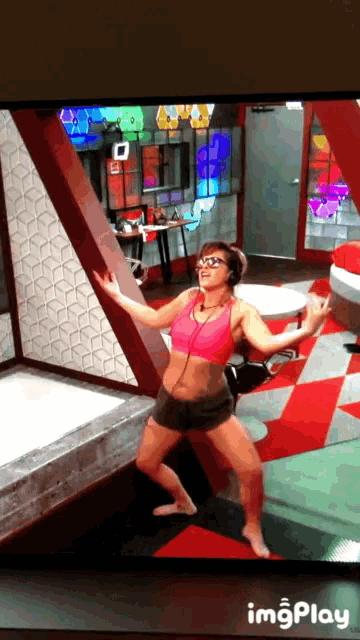 a woman in a pink top and shorts is dancing in a room with a red and white tile floor