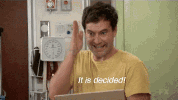 a man in a yellow shirt is giving a high five while holding a laptop and says it is decided .