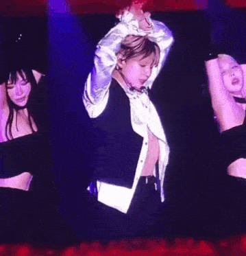 a man in a white shirt is dancing on a stage with his hands in the air