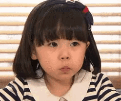 a little girl with short hair is wearing a striped shirt and a headband .