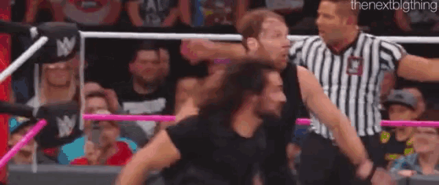 a wrestling match is being held in front of a crowd .