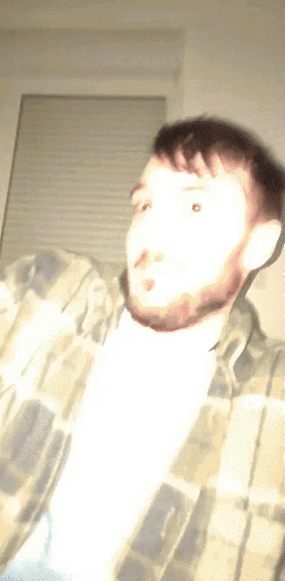 a man in a plaid shirt is looking at the camera