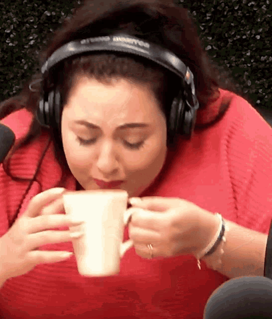 a woman wearing headphones is drinking from a mug