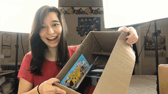 a woman in a red shirt is holding a cardboard box with a picture of a giraffe on it