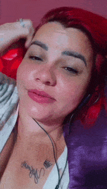 a woman with red hair and a tattoo on her chest wearing headphones .