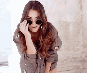 a woman wearing sunglasses and a jacket is posing for the camera .