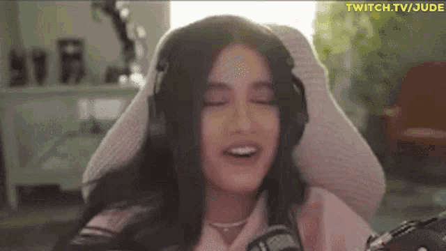 a woman wearing headphones is sitting in a chair with her eyes closed and smiling .