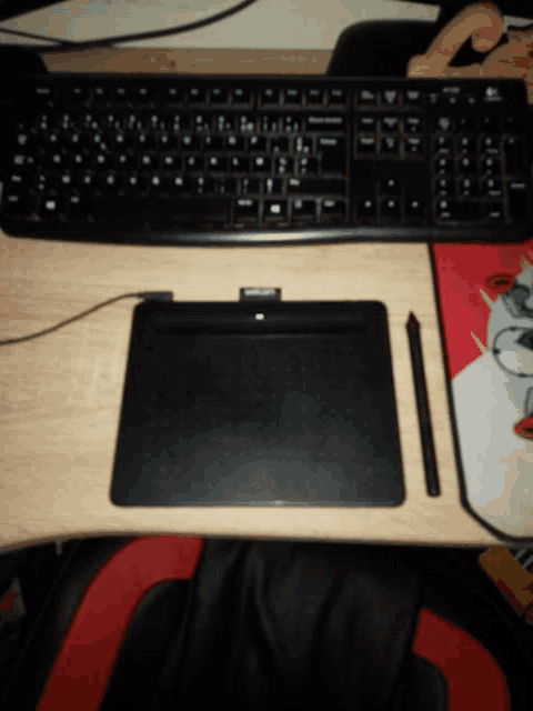 a keyboard and a pen sit on a desk next to a mouse pad