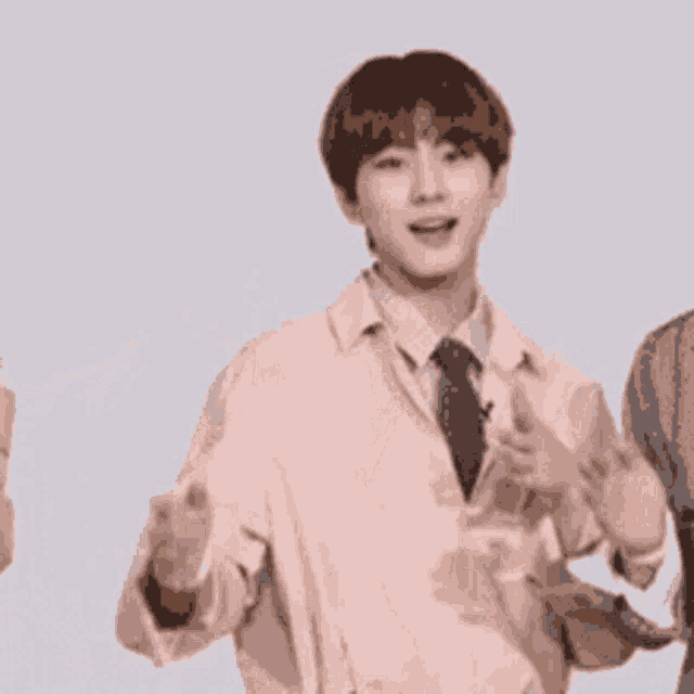 a man in a suit and tie is waving his hands in the air while standing next to two other people .