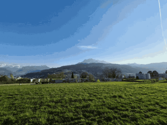 a grassy field with mountains in the background and a blue sky