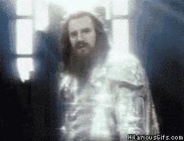 a man with a beard is standing in front of a window with hilariousgifs.com on the bottom right