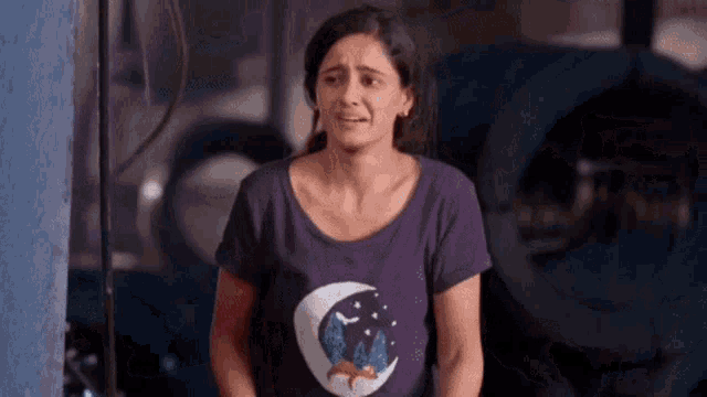 a woman wearing a purple shirt with a fox on it is standing in front of a laundry machine .