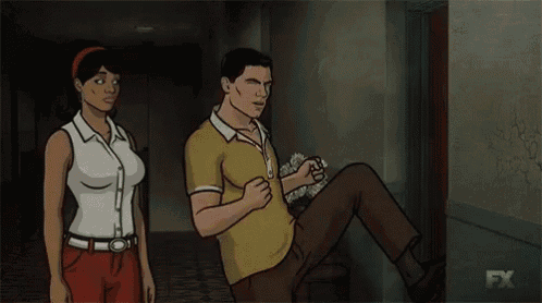 a man and a woman are standing next to each other in a hallway while a man is laying on the floor .