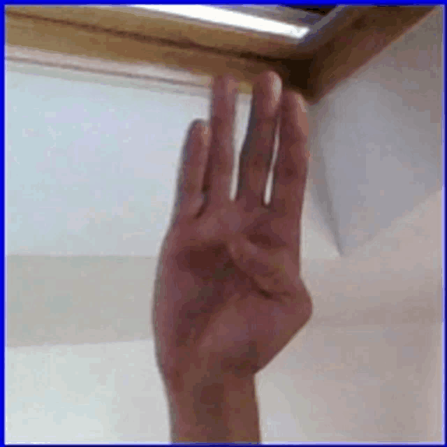 a person 's hand is reaching out towards a skylight