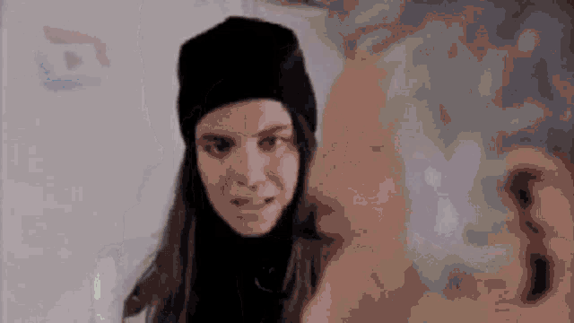 a woman wearing a black hat and a black turtleneck is talking to a man .