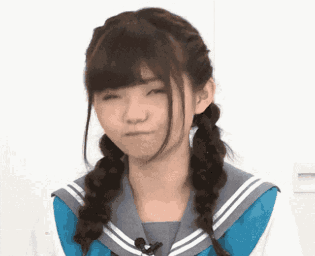 a girl in a school uniform with pigtails making a funny face