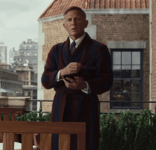 a man in a robe and tie is standing in front of a building