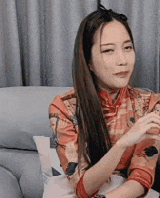 a woman is sitting on a couch with her eyes closed and looking at something .