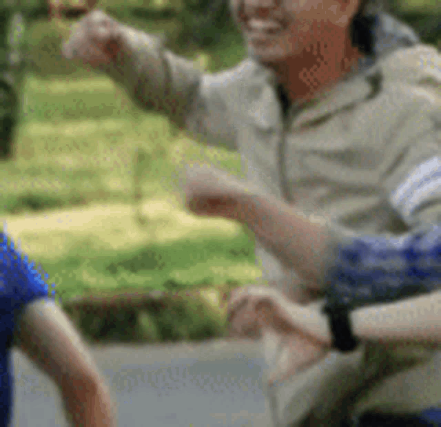 a man and a woman are standing next to each other in a park . the woman is wearing a watch .